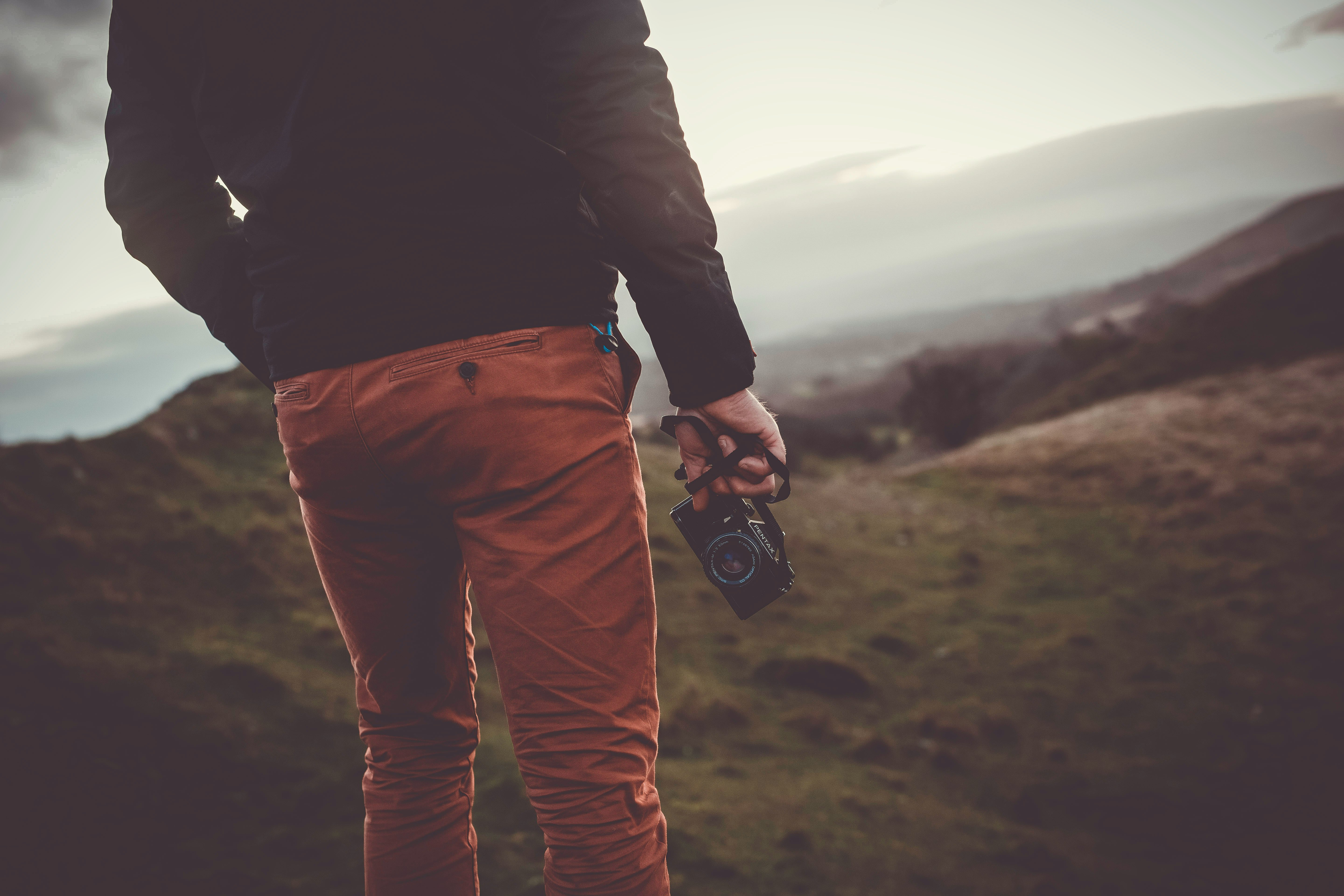 man standing uphill holding black digital camera